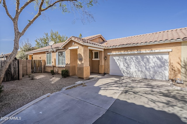 view of front facade with concrete driveway, a tile roof, an attached garage, fence, and stucco siding