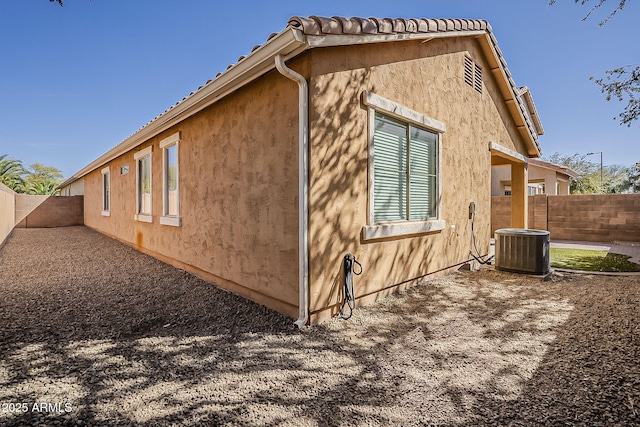 view of property exterior with a fenced backyard, central AC, and stucco siding