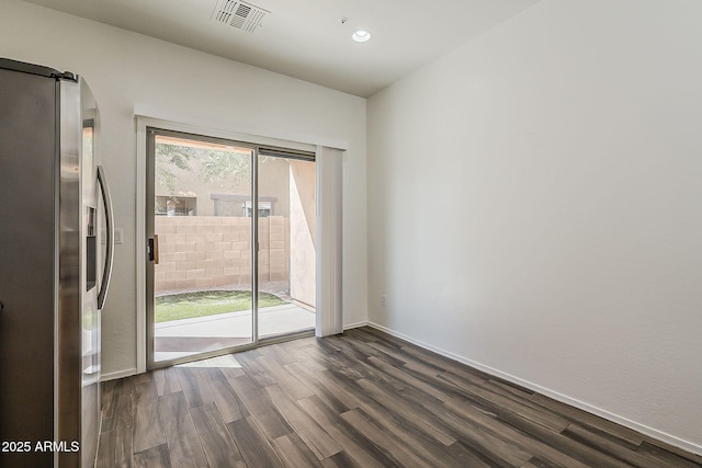 empty room with dark wood-style floors, recessed lighting, visible vents, a barn door, and baseboards