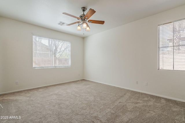 carpeted empty room with baseboards, visible vents, and a ceiling fan