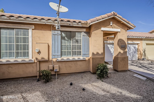 view of front of property with an attached garage, a tile roof, and stucco siding