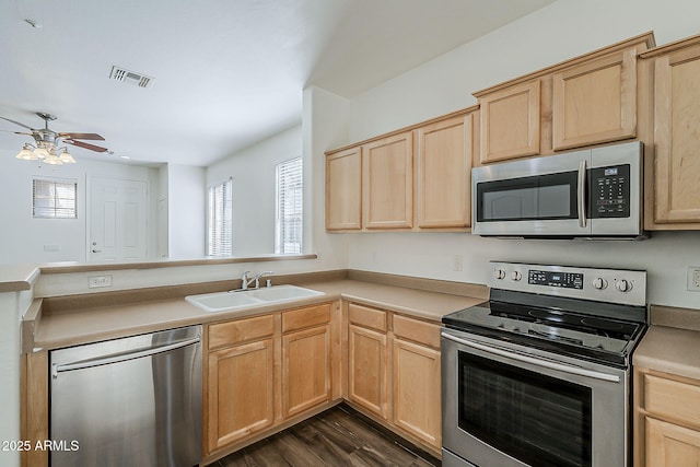 kitchen with light brown cabinets, a peninsula, a sink, visible vents, and appliances with stainless steel finishes