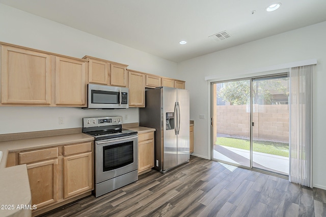 kitchen featuring dark wood-style floors, stainless steel appliances, light brown cabinetry, and visible vents