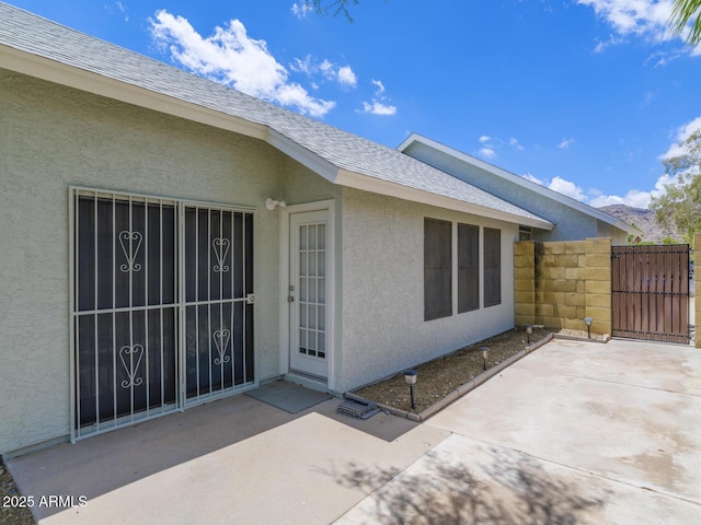 10613 S 41st Pl, Phoenix, AZ 85044 - view of exterior entry featuring a gate, stucco siding, a shingled roof, and a patio area