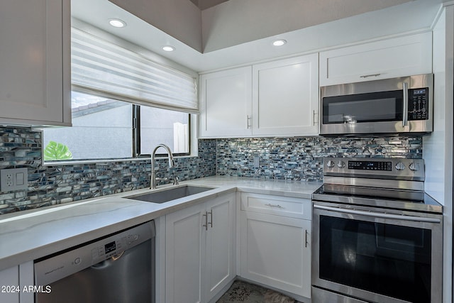 kitchen featuring decorative backsplash, sink, white cabinets, and stainless steel appliances