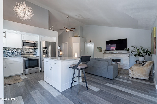 kitchen featuring decorative backsplash, dark hardwood / wood-style flooring, stainless steel appliances, a center island, and white cabinetry