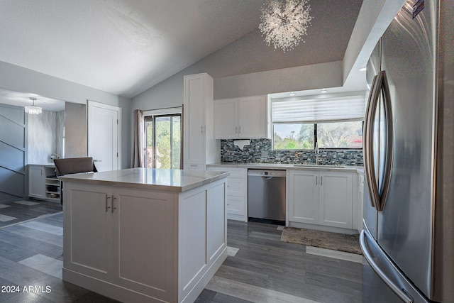 kitchen featuring white cabinetry, a center island, stainless steel appliances, a chandelier, and vaulted ceiling