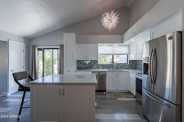 kitchen with appliances with stainless steel finishes, vaulted ceiling, pendant lighting, a center island, and white cabinetry