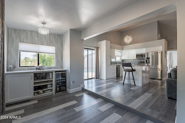 kitchen featuring backsplash, a breakfast bar, stainless steel appliances, pendant lighting, and white cabinets