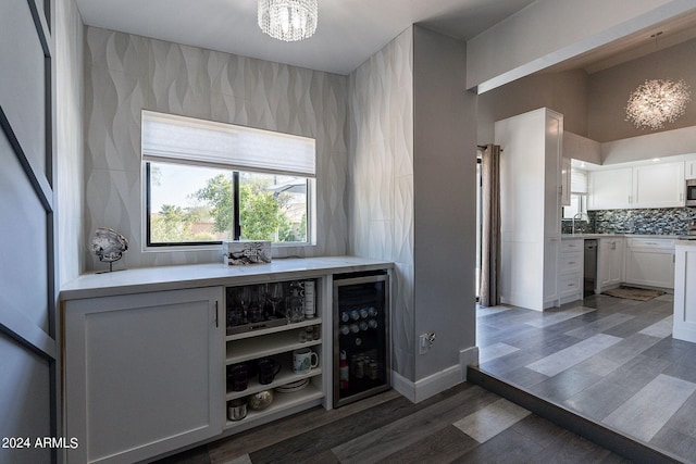 bar with backsplash, an inviting chandelier, dark hardwood / wood-style floors, white cabinetry, and beverage cooler