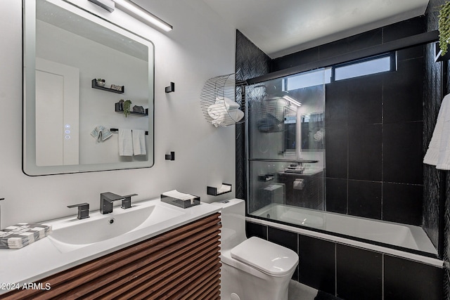 full bathroom featuring vanity, bath / shower combo with glass door, and toilet