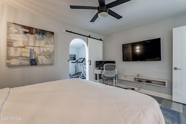 bedroom featuring a barn door, ceiling fan, and hardwood / wood-style floors