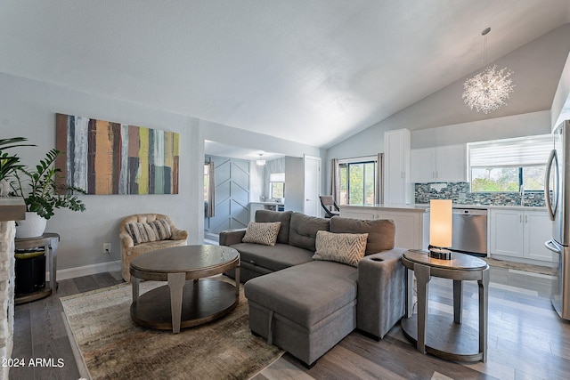 living room with vaulted ceiling, hardwood / wood-style flooring, and an inviting chandelier