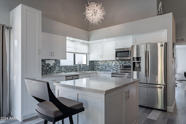 kitchen with appliances with stainless steel finishes, white cabinetry, a kitchen island, and sink