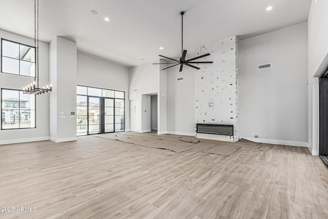 3653 E Runaway Bay Pl, Queen Creek, AZ 85142 - unfurnished living room featuring a towering ceiling, baseboards, light wood-type flooring, recessed lighting, and a ceiling fan