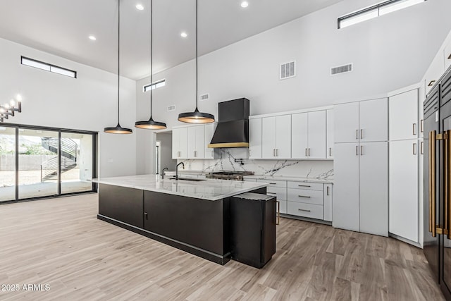 3653 E Runaway Bay Pl, Queen Creek, AZ 85142 - kitchen with a towering ceiling, custom range hood, a sink, light wood-type flooring, and an island with sink
