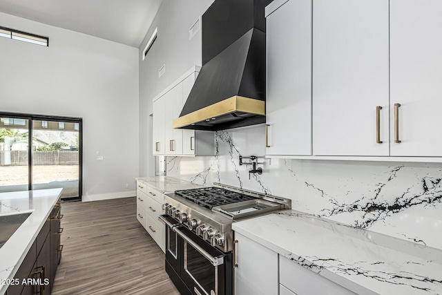 3653 E Runaway Bay Pl, Queen Creek, AZ 85142 - kitchen with wall chimney exhaust hood, double oven range, a towering ceiling, tasteful backsplash, and white cabinets