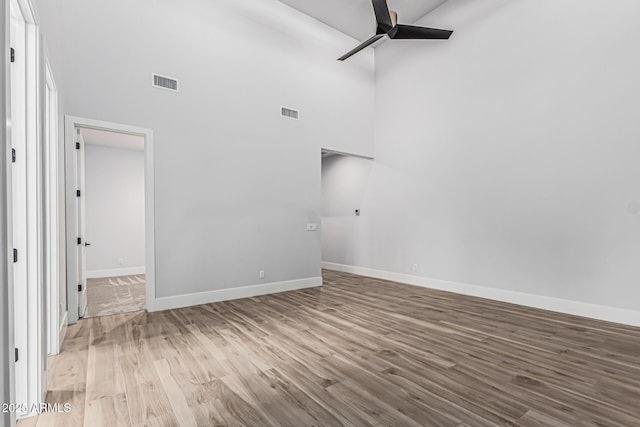 3653 E Runaway Bay Pl, Queen Creek, AZ 85142 - spare room with a ceiling fan, a high ceiling, wood finished floors, and baseboards