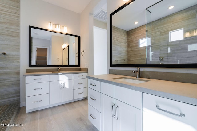 bathroom with a tile shower and vanity