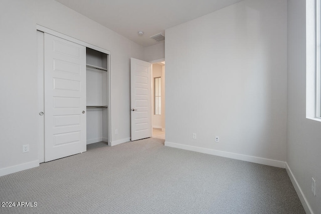 unfurnished bedroom featuring light colored carpet and a closet