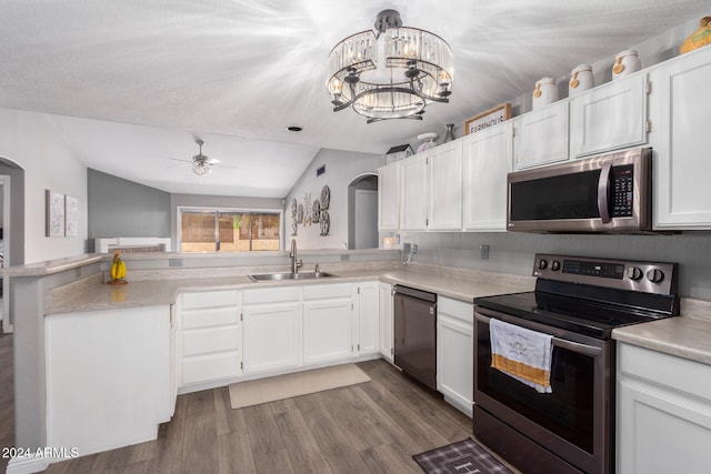 kitchen featuring sink, kitchen peninsula, lofted ceiling, white cabinets, and appliances with stainless steel finishes