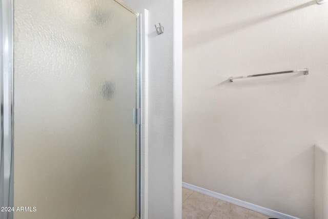 bathroom with tile patterned floors and a shower with door