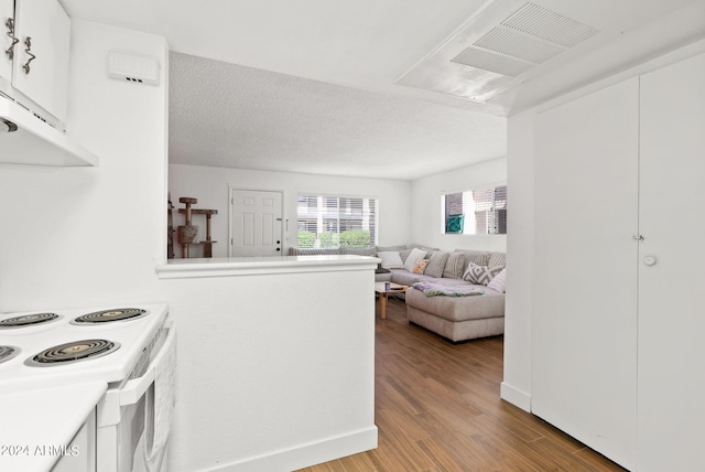 kitchen featuring wood-type flooring, white electric range oven, a textured ceiling, and white cabinetry