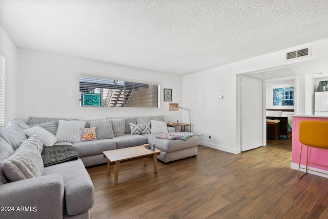 living room featuring a textured ceiling and dark wood-type flooring