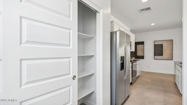 kitchen featuring visible vents, built in features, electric stove, stainless steel fridge, and white cabinetry