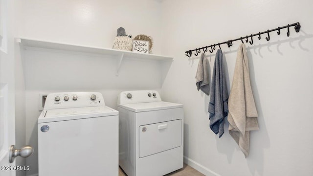 washroom featuring washing machine and clothes dryer, laundry area, and baseboards