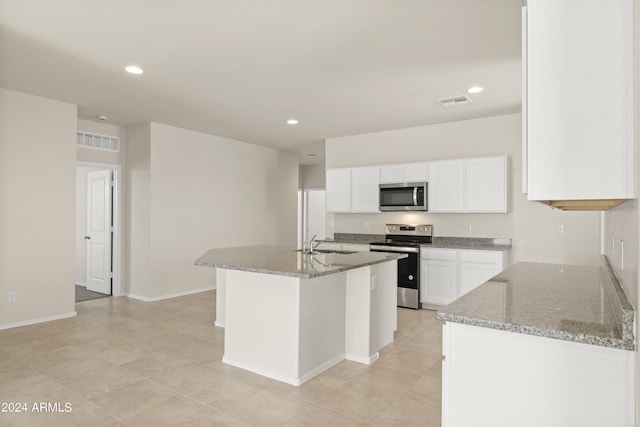 kitchen with white cabinets, stainless steel appliances, light stone counters, and a sink