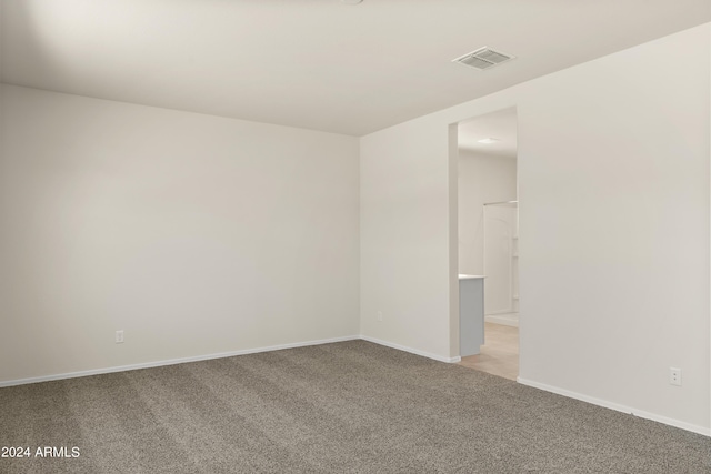 empty room featuring baseboards, light colored carpet, and visible vents