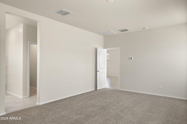 spare room with visible vents, baseboards, and light carpet