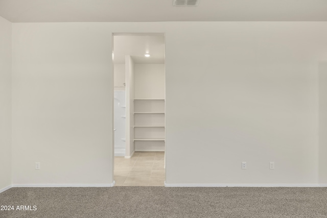 spare room featuring light tile patterned floors, baseboards, light carpet, and visible vents