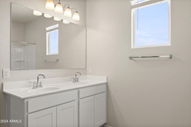 bathroom with a sink, walk in shower, and double vanity