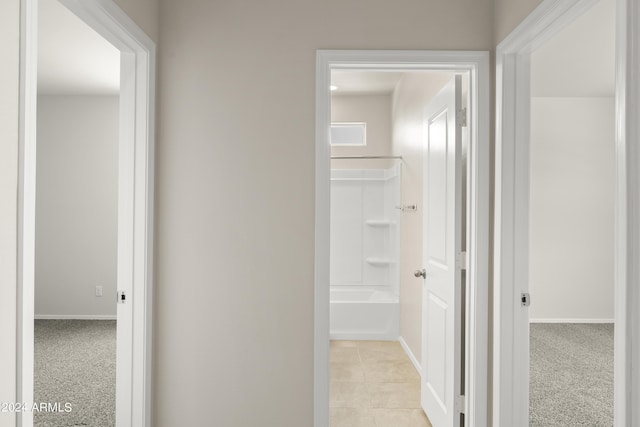 corridor with light tile patterned floors and baseboards