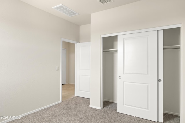 unfurnished bedroom with baseboards, visible vents, light carpet, and a closet
