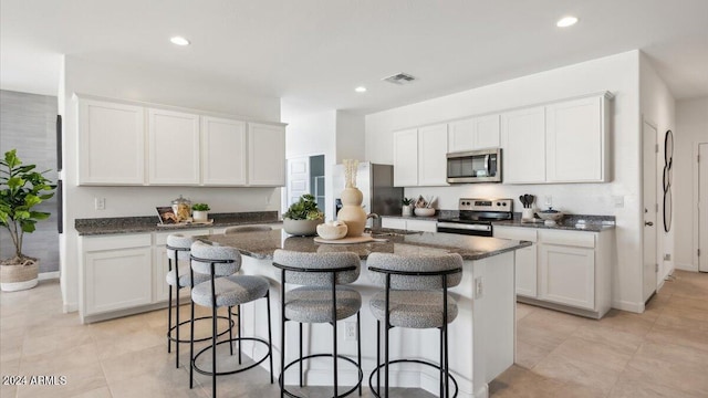 kitchen featuring a breakfast bar area, a kitchen island with sink, stainless steel appliances, recessed lighting, and visible vents