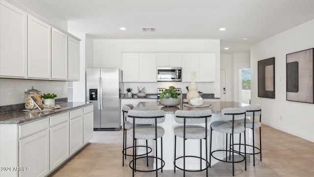 kitchen with recessed lighting, dark stone counters, appliances with stainless steel finishes, and a breakfast bar area