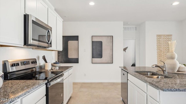 kitchen featuring baseboards, white cabinetry, a sink, stone counters, and stainless steel appliances