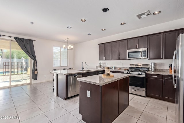 kitchen featuring visible vents, a sink, stainless steel appliances, a peninsula, and light tile patterned flooring