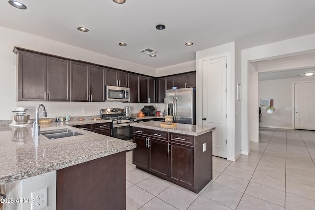 kitchen featuring light tile patterned floors, visible vents, a sink, stainless steel appliances, and dark brown cabinetry