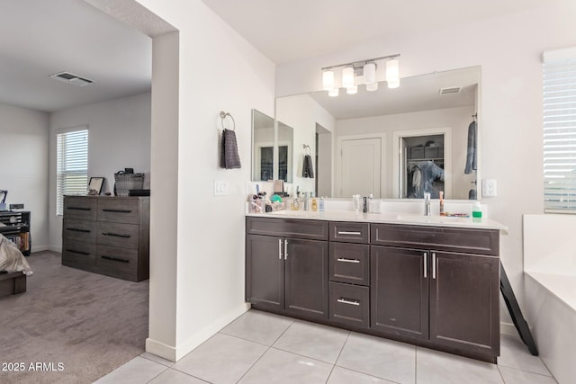 full bathroom featuring double vanity, visible vents, baseboards, and a bathtub