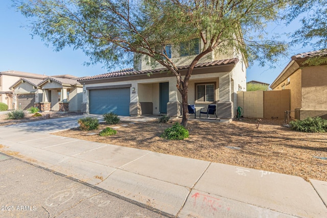 view of front of property with concrete driveway, a tiled roof, fence, and stucco siding