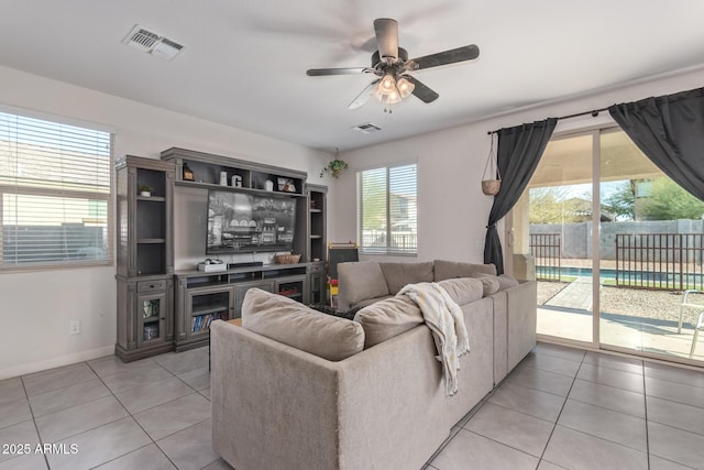 living area featuring light tile patterned floors, visible vents, baseboards, and a ceiling fan