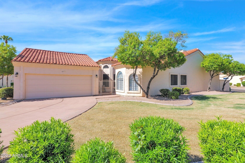 mediterranean / spanish-style house with concrete driveway, stucco siding, a tile roof, and a front yard