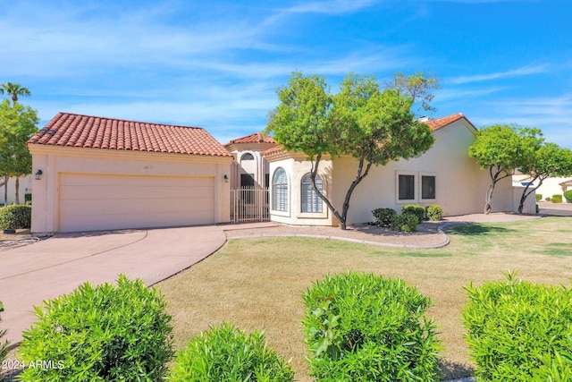 mediterranean / spanish-style house with concrete driveway, stucco siding, a tile roof, and a front yard