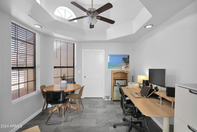 office with a tray ceiling and ceiling fan