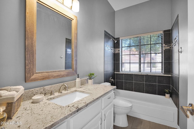 full bathroom featuring wood-type flooring, tiled shower / bath, vanity, and toilet