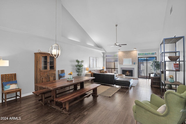 living room featuring high vaulted ceiling, a large fireplace, ceiling fan with notable chandelier, and dark wood-type flooring